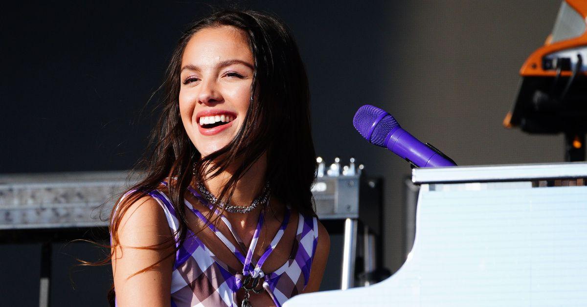 Olivia Rodrigo com sorriso enorme no rosto ao piano