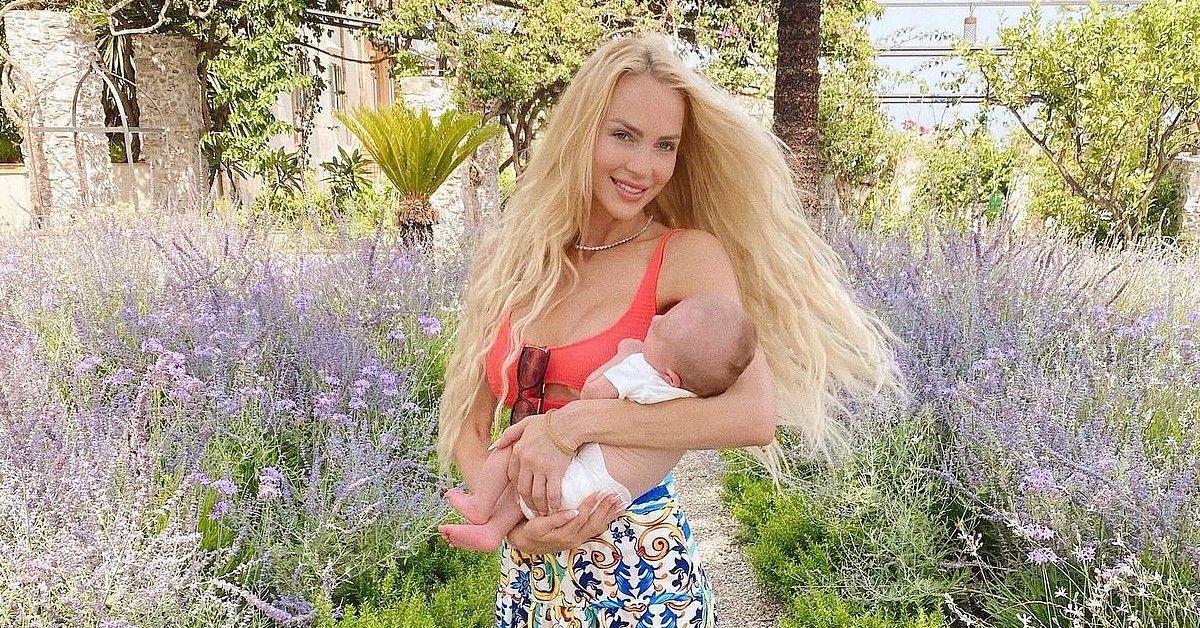 Christine Quinn em Taormina segurando seu bebê na natureza.