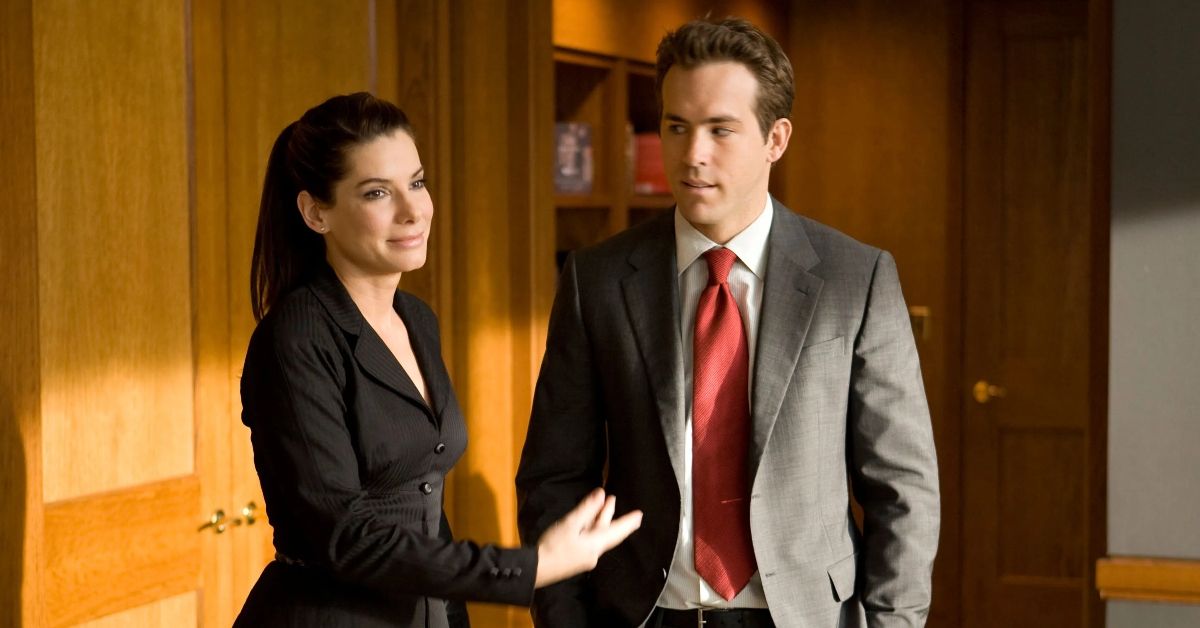 Sandra Bullock e Ryan Reynolds de terno em escritório