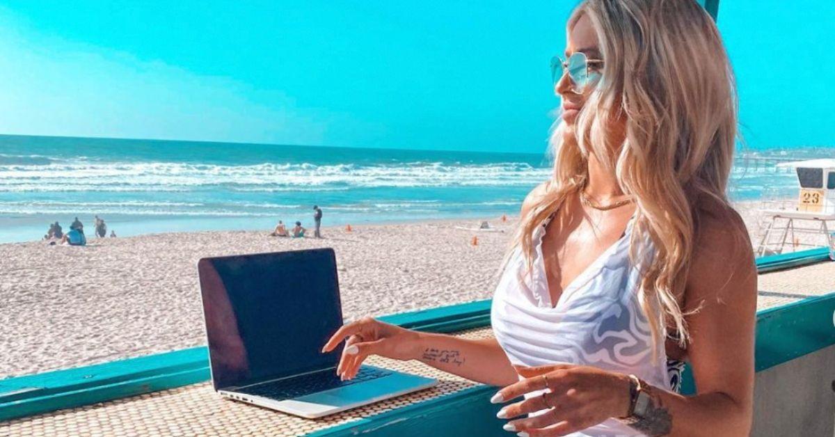 Scarlett Bentley trabalhando em um computador perto da praia